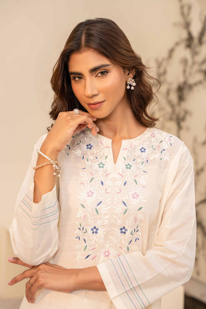 A white cotton suit with intricate embroidery, featuring a long sleeve design.